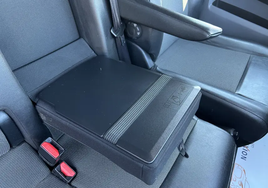 Détail de l'accoudoir central noir entre les sièges avant du Citroën Jumpy blanc, vue intérieure côté droit.