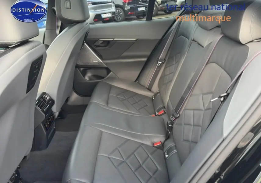 Vue intérieure arrière côté droit de la BMW Série 5 i5 M60 2024 avec sièges cuir noirs et surpiqûres contrastées.