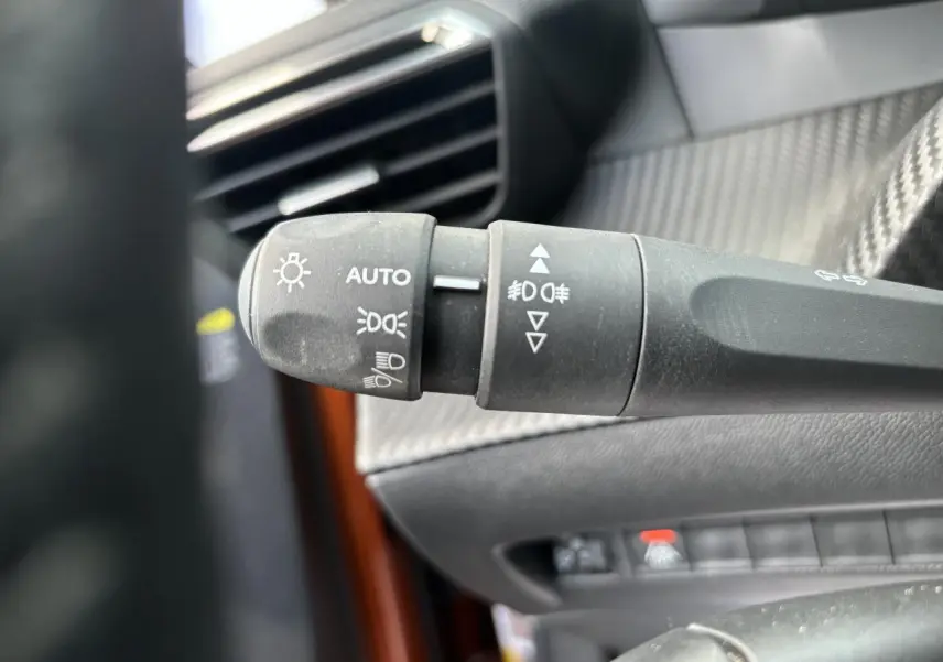 Gros plan sur la commande des phares à gauche du volant dans l’habitacle du Peugeot 2008 Orange Fusion 2021.