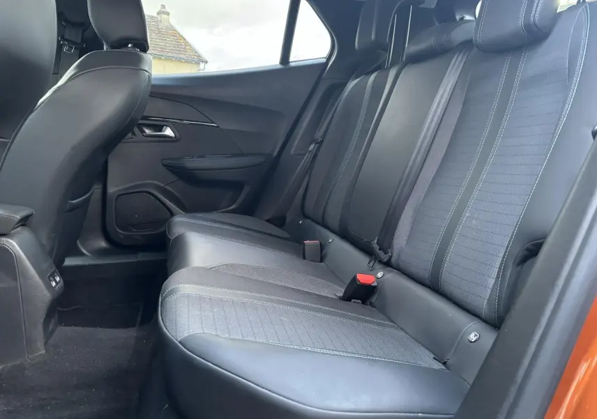 Vue intérieure de la banquette arrière côté droit de la Peugeot 2008 orange fusion, avec sièges en tissu et cuir noir.