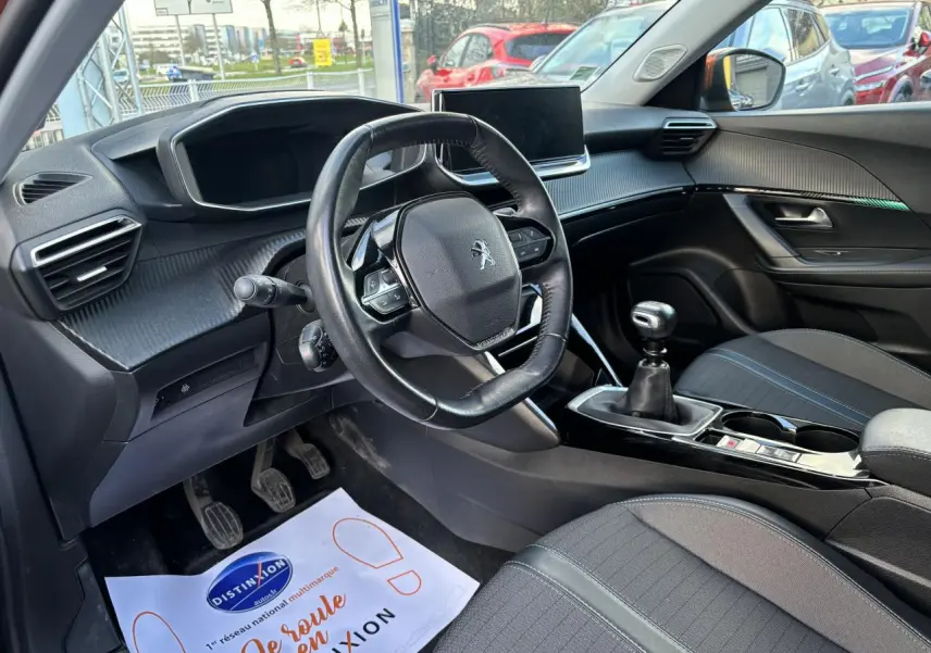 Intérieur de la Peugeot 2008 2021, vue côté conducteur, volant compact cuir et levier de vitesse manuel visibles.