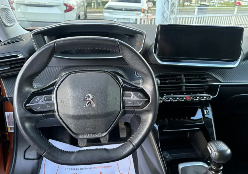 Vue intérieure centrée sur le volant compact cuir du Peugeot 2008 2021 avec écran tactile et levier de vitesse manuel.