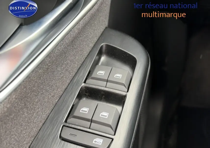 Gros plan sur les commandes des vitres électriques côté gauche d’un MG ZS Hybrid blanc, avec finition noire intérieure.