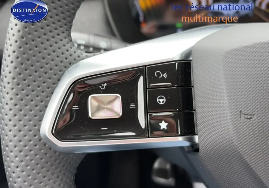 Gros plan sur les commandes noires du volant perforé du MG ZS Hybrid blanc, avec boutons multifonctions visibles.