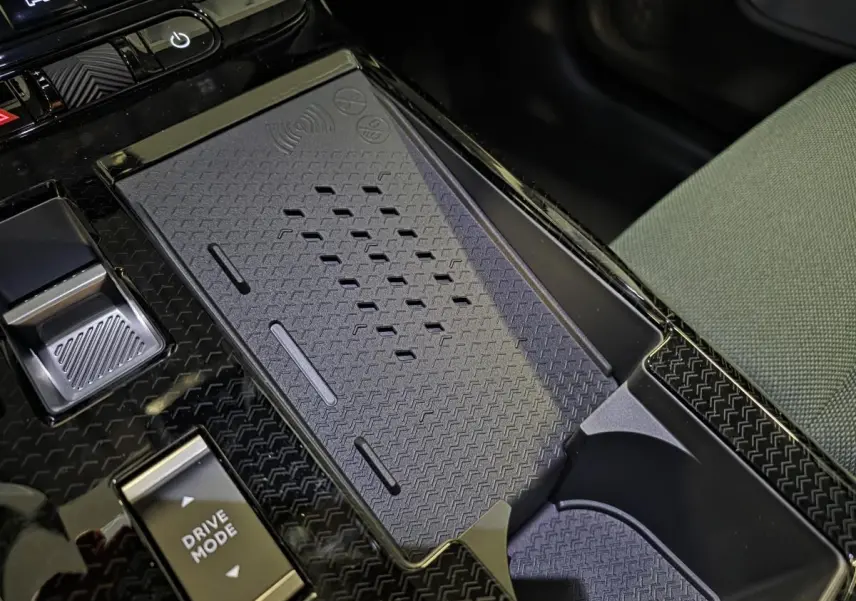 Gros plan sur la console centrale noire brillante du Citroën C5 Aircross 2026 avec zone de recharge sans fil et bouton Drive Mode.