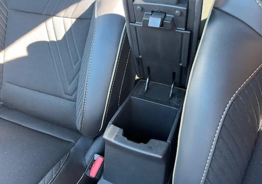 Vue rapprochée de la console centrale noire ouverte entre les sièges avant noirs du Renault Symbioz 2025.