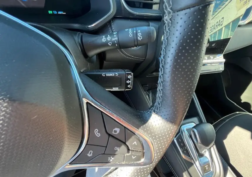 Gros plan sur le volant en cuir perforé et la commande de boîte automatique du Renault Symbioz noir, intérieur moderne et soigné.