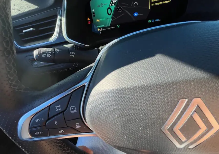 Gros plan sur le volant noir et le tableau de bord numérique du Renault Symbioz 2025, affichant les commandes de conduite.