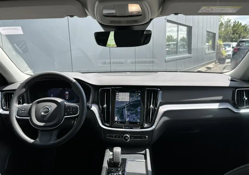 Vue intérieure du tableau de bord de la Volvo S60 2024 avec écran tactile GPS et volant multifonction noir.