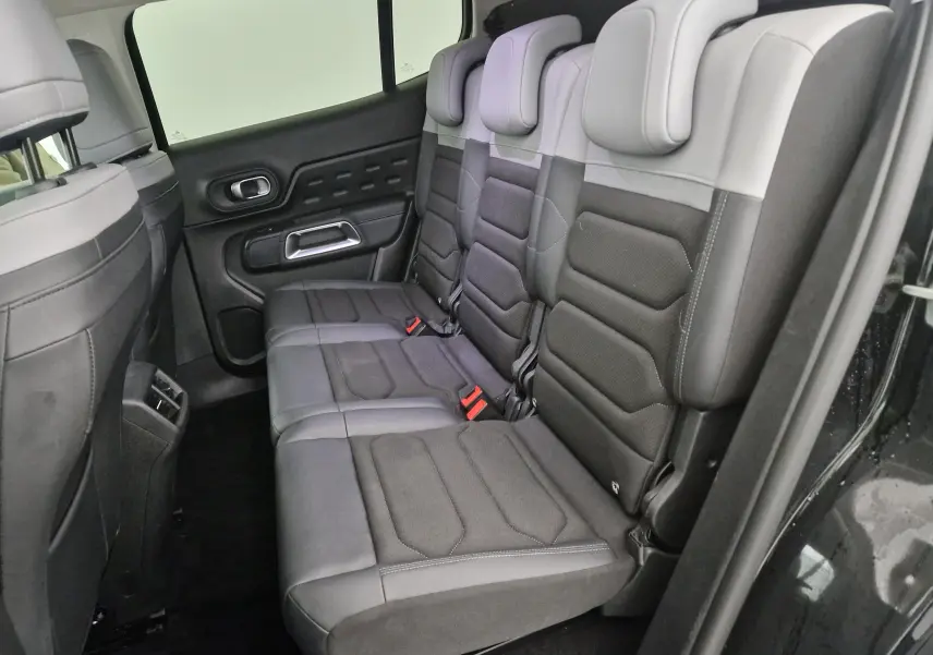 Vue latérale des sièges arrière en tissu et cuir gris foncé du Citroën C5 Aircross noir 2024, avec ceintures rouges visibles.