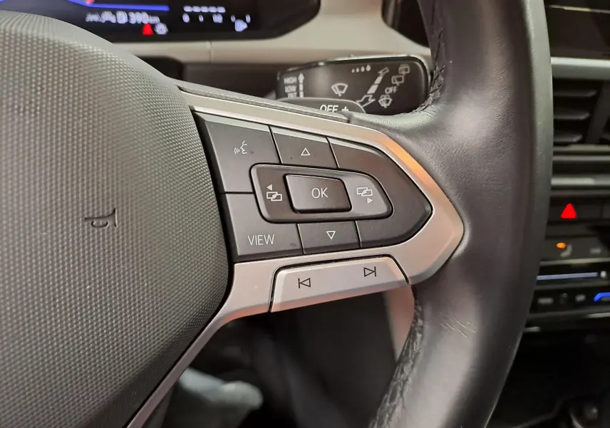 Gros plan sur les commandes au volant du Volkswagen T-Roc 2024, avec boutons multifonctions et volant cuir noir.