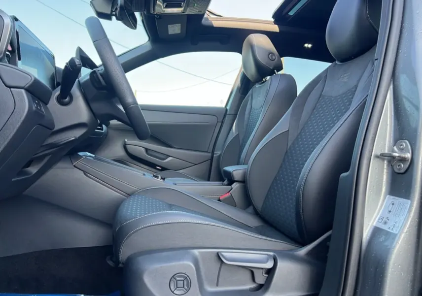 Vue intérieure côté conducteur du Volkswagen T-Roc gris loup, sièges R-Line en tissu et alcantara avec surpiqûres blanches.