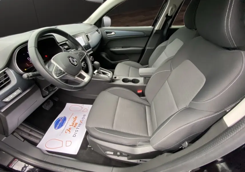 Vue intérieure côté conducteur du Renault Arkana noir 2024, sièges tissu gris et tableau de bord avec écran tactile central.