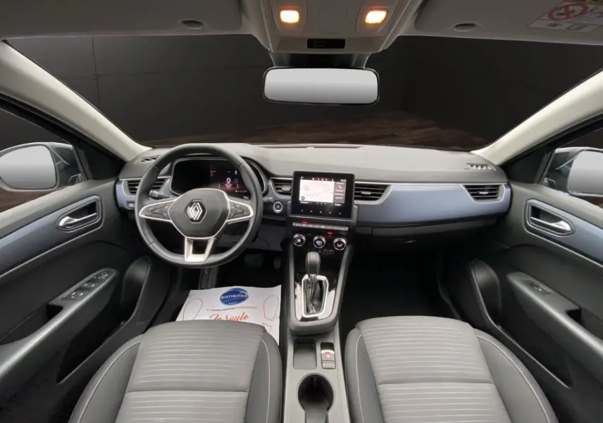 Vue intérieure avant du Renault Arkana noir 2024, tableau de bord moderne avec écran tactile central et volant multifonctions.