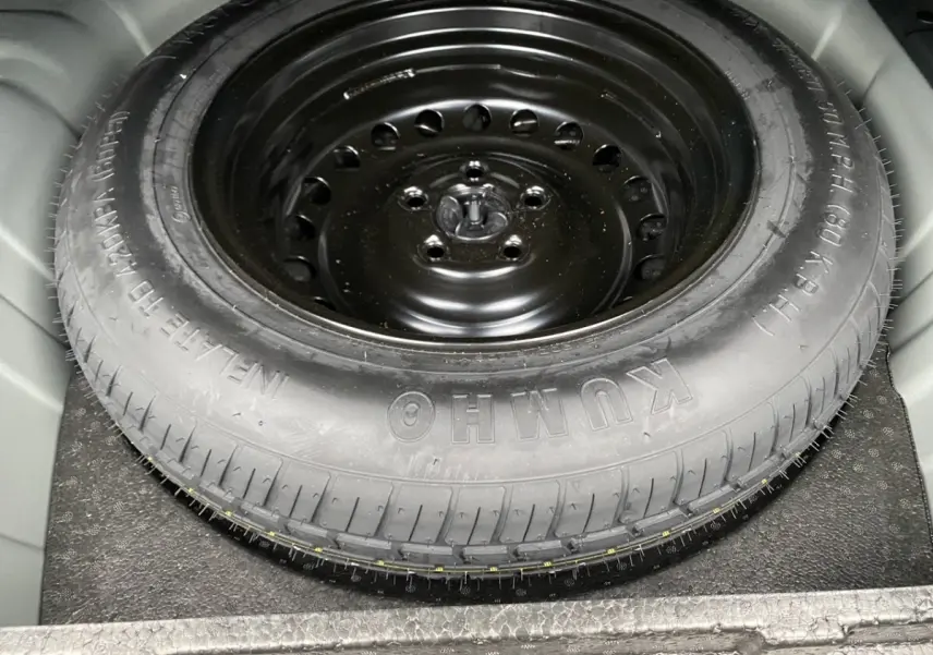 Gros plan sur la roue de secours noire en acier dans le coffre d’un Renault Arkana noir 2024.
