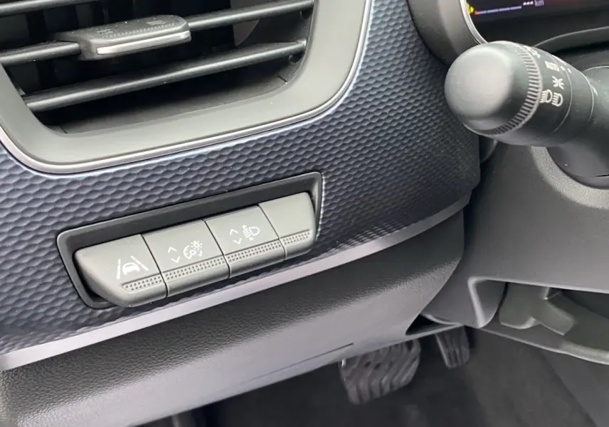 Détail intérieur côté gauche du tableau de bord noir du Renault Arkana 2024 avec boutons de réglage des aides à la conduite.