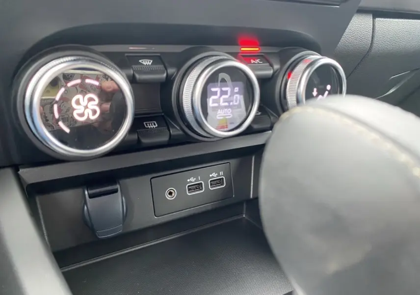 Détail intérieur du tableau de bord du Renault Arkana 2024, montrant les commandes de climatisation et ports USB.