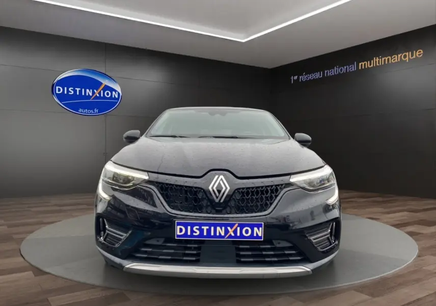 Vue frontale d'une Renault Arkana noire 2024 avec calandre noire et phares LED allumés en showroom.