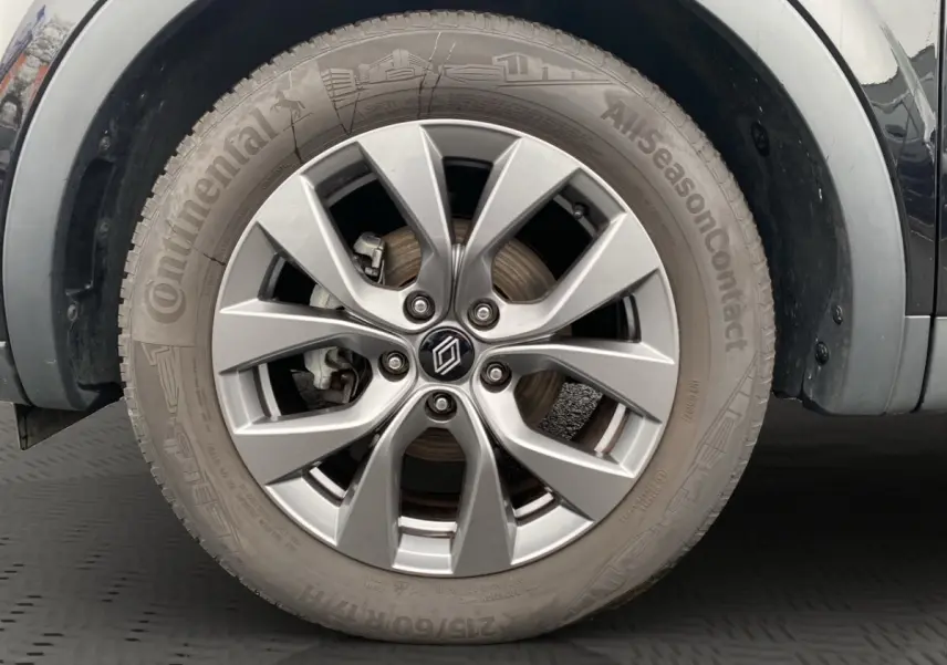 Gros plan sur la roue avant droite du Renault Arkana noir, jante alliage argentée à 5 doubles branches.
