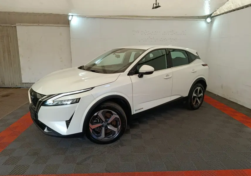 Vue 3/4 avant droit du Nissan Qashqai e-Power blanc avec jantes alliage et feux LED dans un espace fermé.