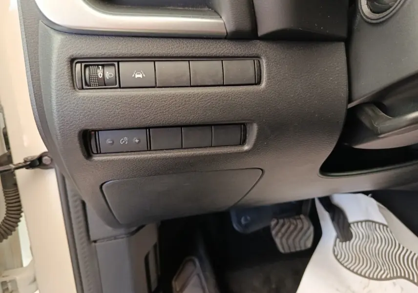 Vue rapprochée des commandes de réglage des phares et aide à la conduite côté gauche du tableau de bord noir du Nissan Qashqai blanc 2024.