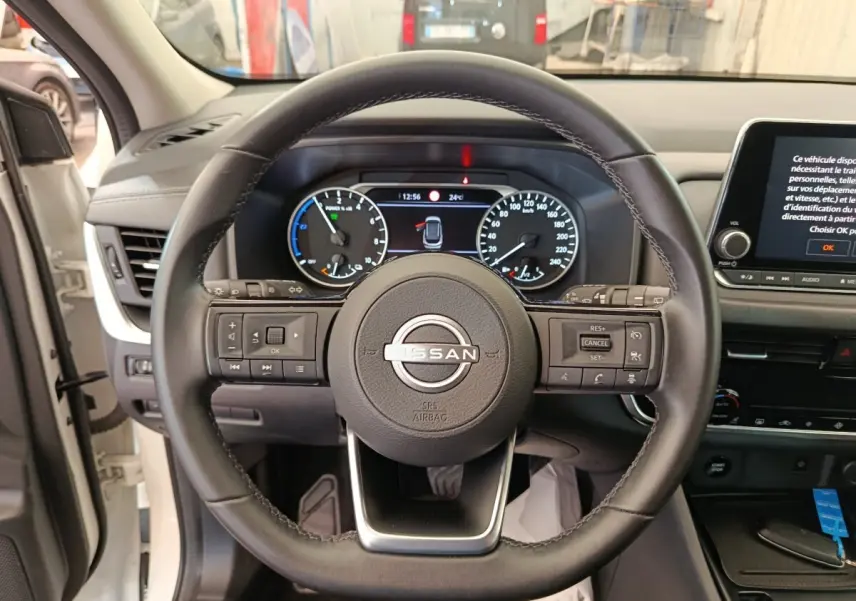 Vue frontale du volant en cuir noir du Nissan Qashqai e-Power 2024 avec tableau de bord digital et écran tactile central.