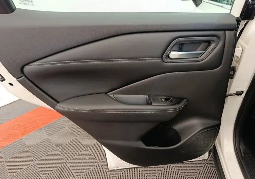Porte intérieure côté gauche du Nissan Qashqai e-Power blanc, avec garniture noire et poignée argentée.