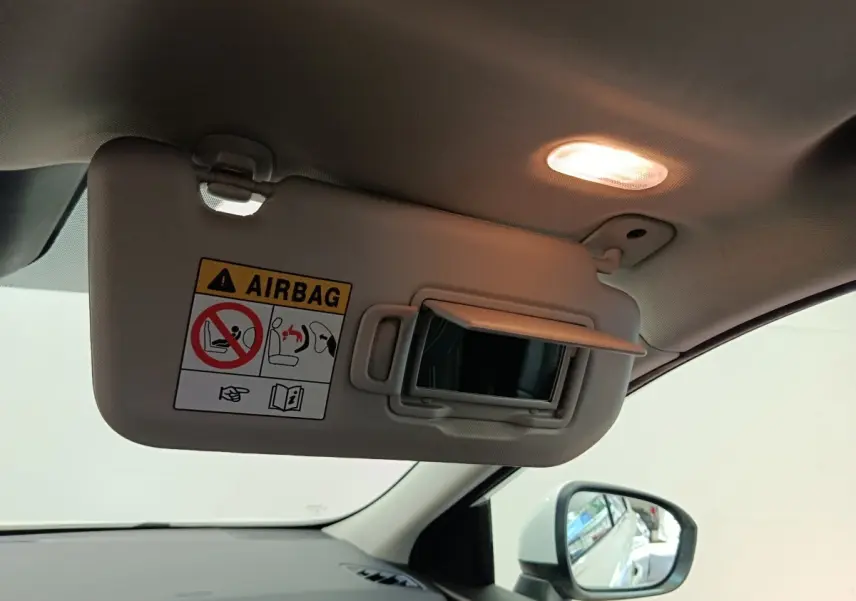 Pare-soleil côté conducteur beige avec miroir ouvert et lumière intérieure allumée dans un Nissan Qashqai blanc 2024.