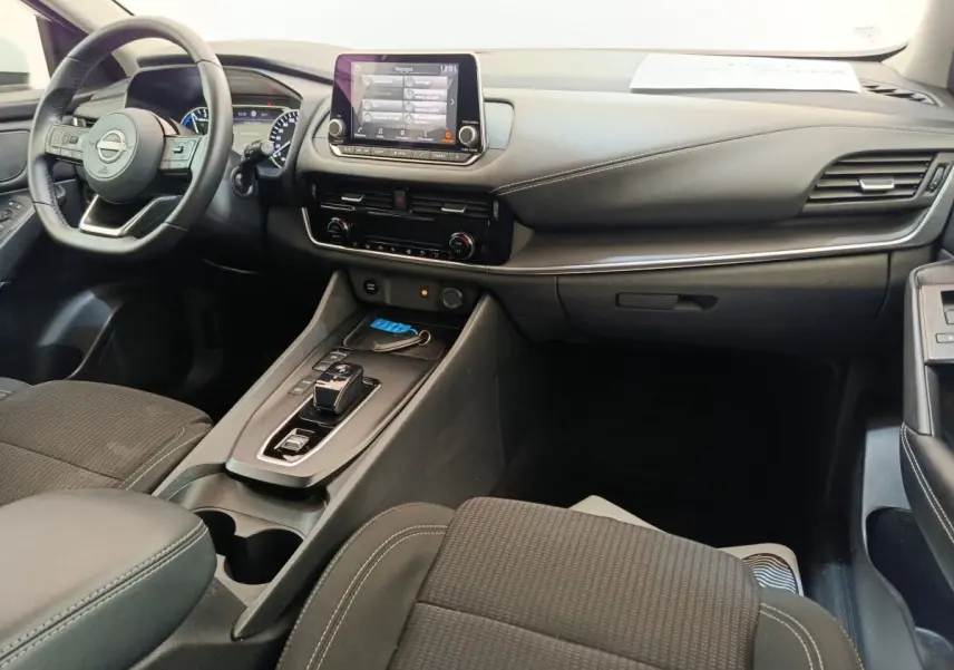 Intérieur noir du Nissan Qashqai e-Power 2024 vu côté passager, avec tableau de bord et écran tactile central.