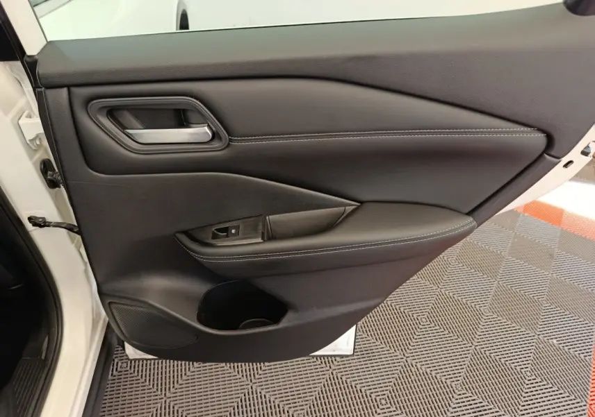 Vue intérieure de la porte avant gauche noire du Nissan Qashqai e-Power 2024 avec poignée et commande de fenêtre.