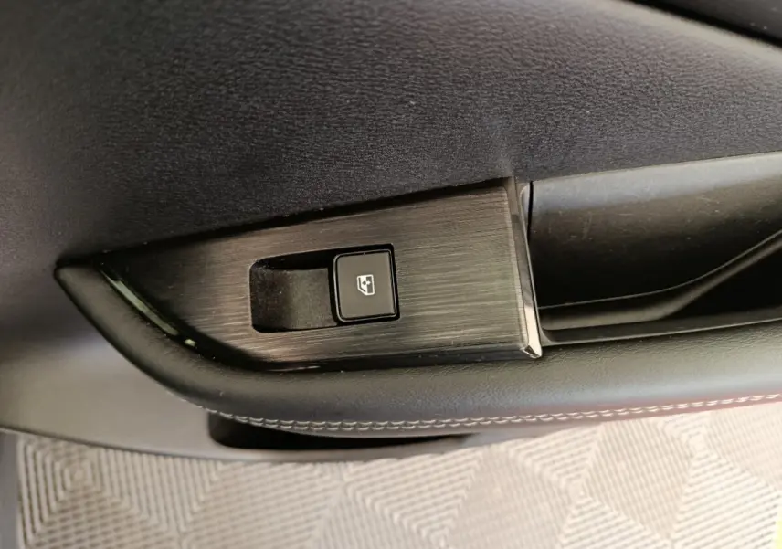 Gros plan sur le bouton de commande de la vitre électrique sur la porte intérieure noire du Nissan Qashqai e-Power 2024.