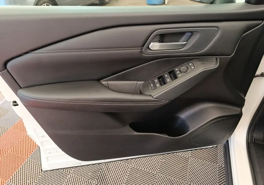 Vue intérieure côté gauche de la porte avant d’un Nissan Qashqai blanc, avec commandes électriques et accoudoir noir.