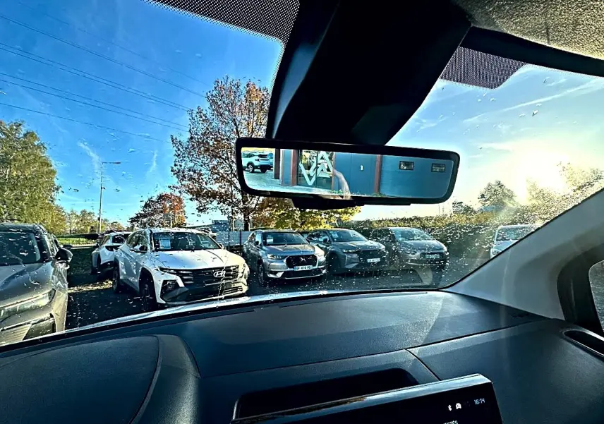 Vue intérieure du pare-brise et rétroviseur d’un Citroën Berlingo blanc, avec plusieurs voitures visibles à l’extérieur.