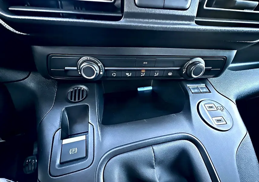 Détail de la console centrale noire du Citroën Berlingo Fourgon M diesel 100, avec commandes clim et prises USB visibles.