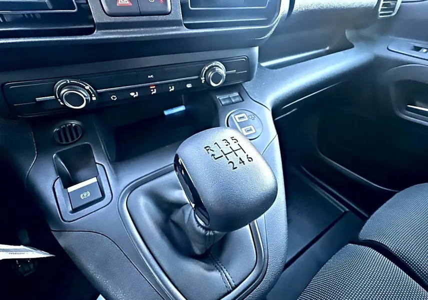 Gros plan sur le levier de vitesses manuel noir du Citroën Berlingo Fourgon blanc, avec tableau de bord et commandes visibles.