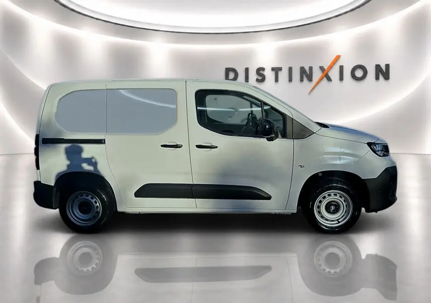 Profil droit du Citroën Berlingo Fourgon blanc avec porte latérale coulissante, roues acier et logo Distinxion en arrière-plan.