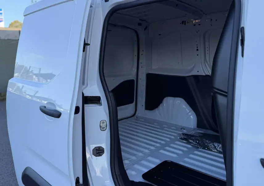 Vue latérale droite du Peugeot Partner blanc Icy 2026 avec porte coulissante ouverte sur l'espace de chargement vide.