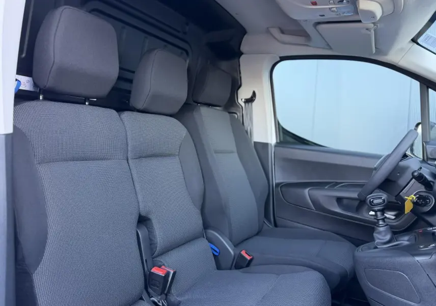 Vue intérieure côté droit du Peugeot Partner 2026 blanc Icy, montrant la banquette passager 2 places et le siège conducteur.