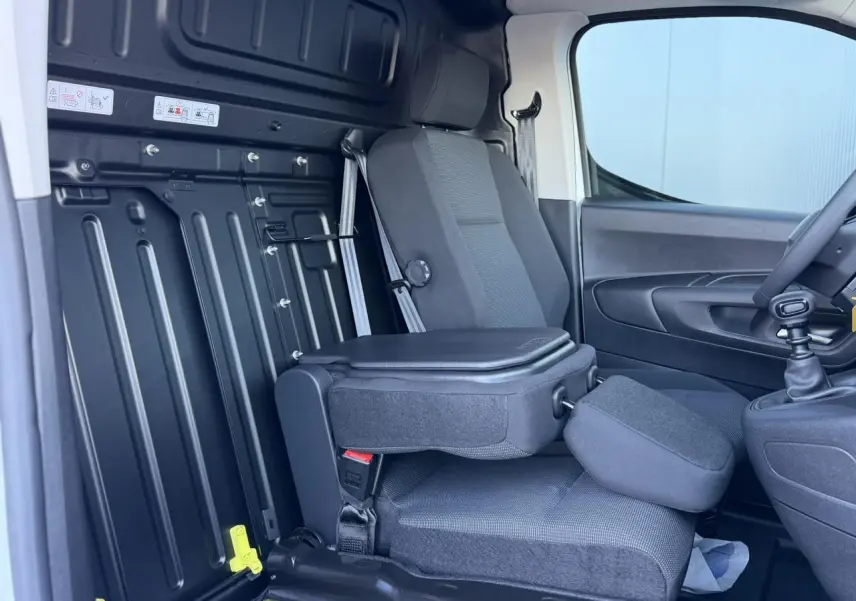 Vue intérieure côté passager avant du Peugeot Partner 2026 blanc Icy, montrant la banquette cabine Extenso avec tablette écritoire rabattable.