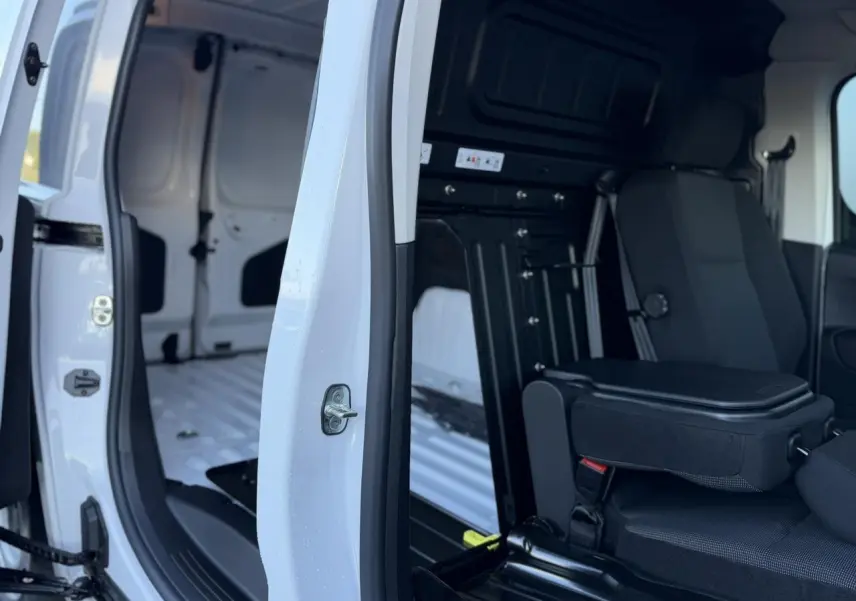 Vue intérieure côté droit du Peugeot Partner blanc Icy, montrant la cabine Extenso avec banquette passager rabattable.