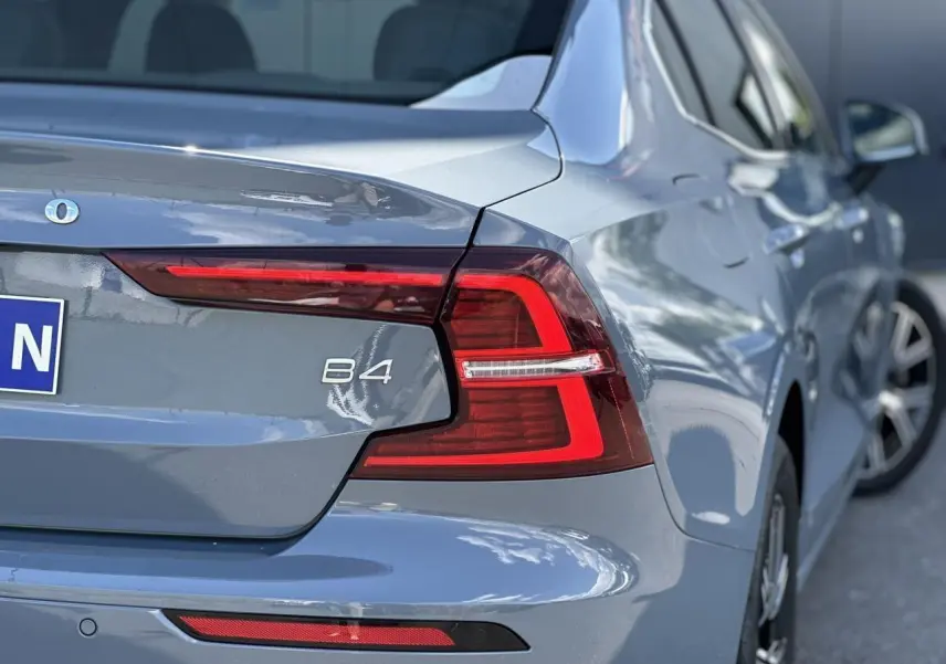 Vue arrière droite d'une Volvo S60 B4 gris Thunder avec feux LED et logo B4 visible sur le coffre