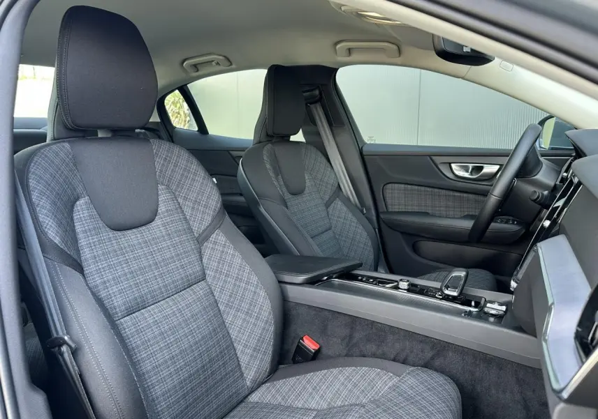 Intérieur de la Volvo S60 B4 2024 vu côté droit, sièges tissu gris à motif tartan et console centrale moderne.