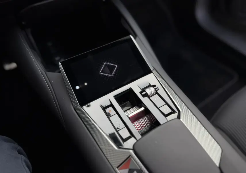 Gros plan sur la console centrale du DS4 2025, finition noire avec commandes tactiles et molette métallique texturée.