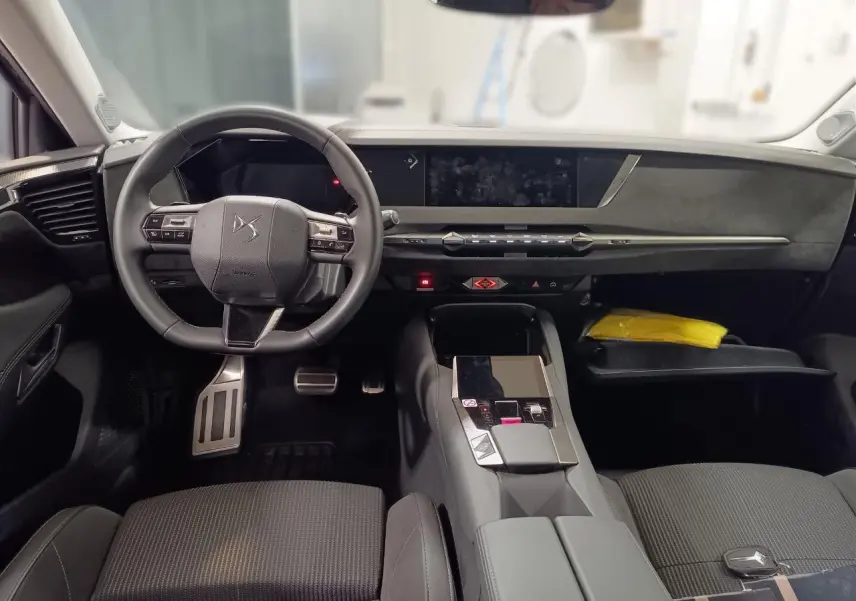Intérieur du DS4 2025 vu de face, tableau de bord et volant cuir noir avec console centrale moderne.