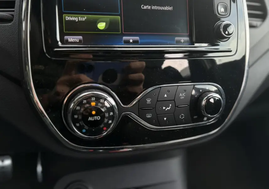 Gros plan sur la console centrale noire brillante du Renault Captur 1.5 DCI avec écran tactile et commandes de climatisation.