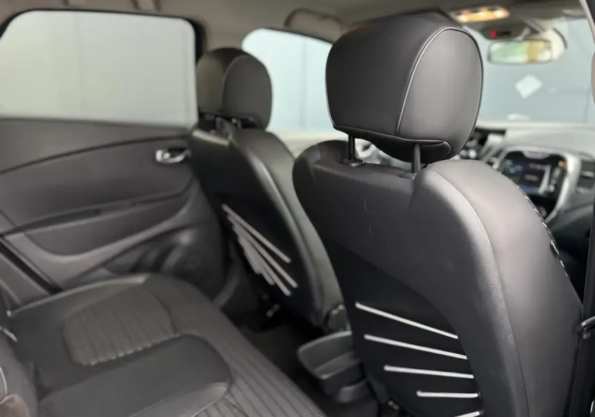 Vue intérieure arrière du Renault Captur 2017, sièges noirs en TEP/textile avec détails gris, plancher et porte côté gauche visibles.