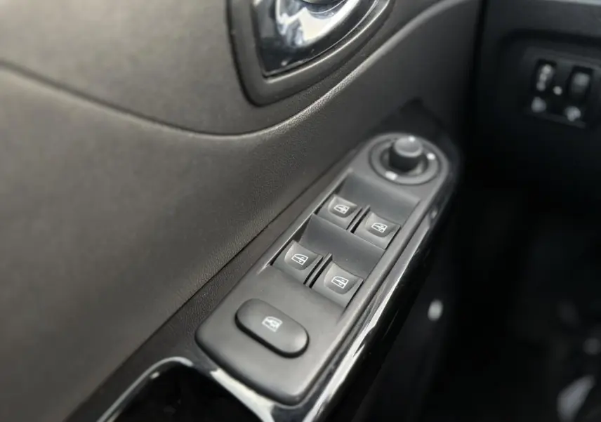 Gros plan sur les commandes des vitres électriques côté conducteur du Renault Captur gris Cassiopée, intérieur noir.