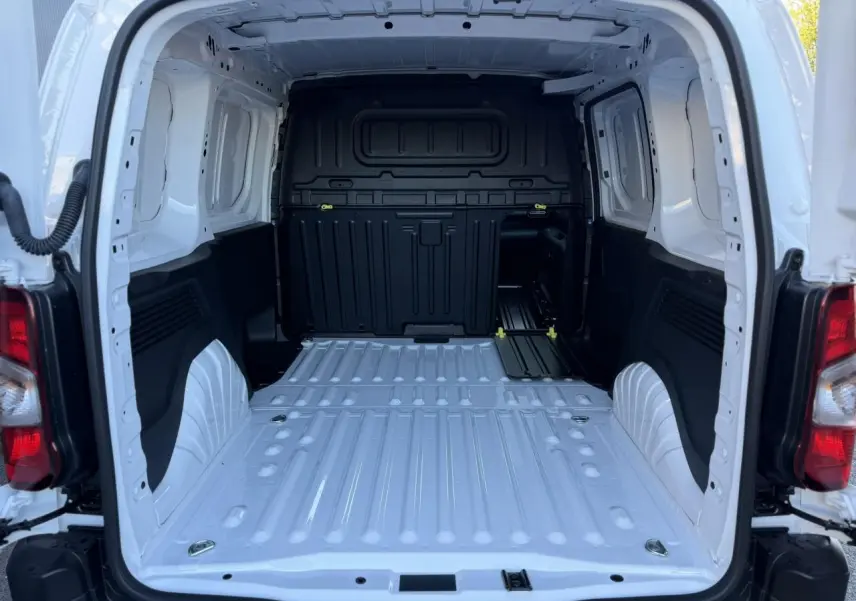 Vue arrière ouverte du coffre blanc Icy du Peugeot Partner 2026, montrant l'espace de chargement tôlé et les fixations au sol.