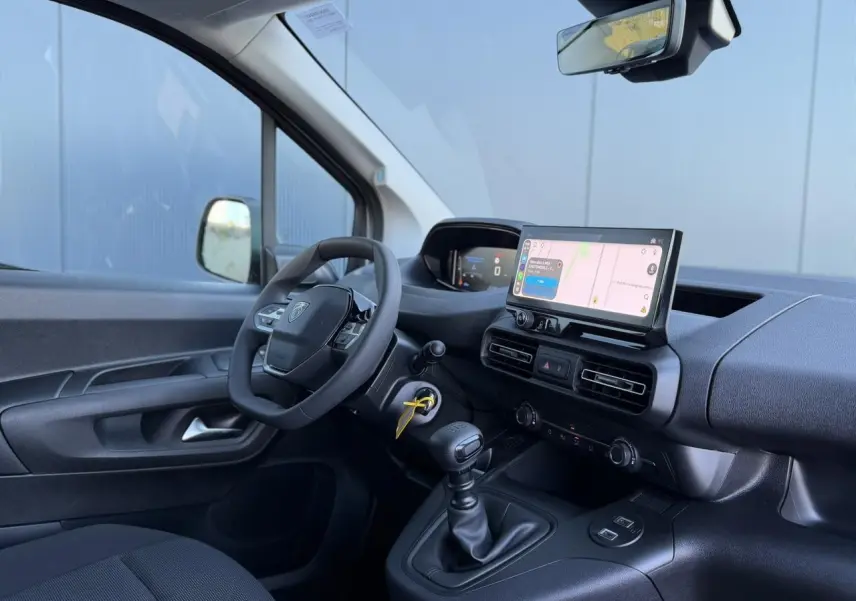 Vue intérieure côté conducteur du Peugeot Partner blanc Icy, avec tableau de bord moderne et écran tactile central.