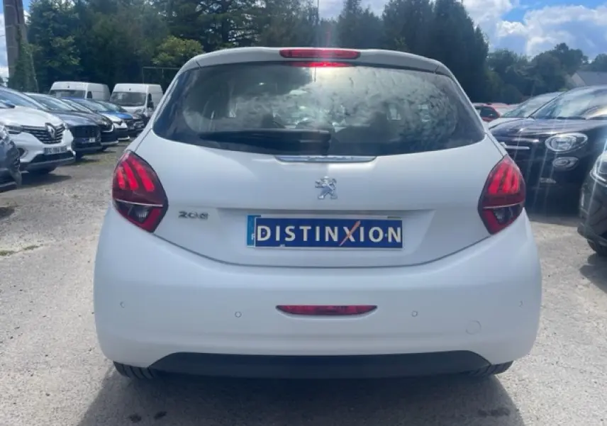 Vue arrière d'une Peugeot 208 blanche perle avec feux arrière rouges et plaque Distinxion visible.